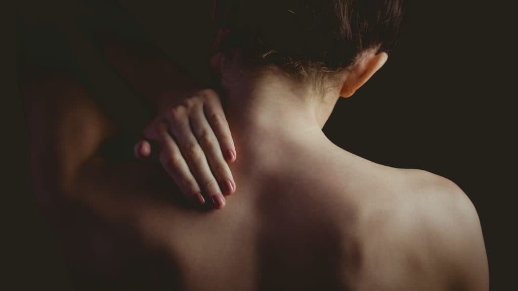 nude-woman-with-a-neck-injury-on-black-background