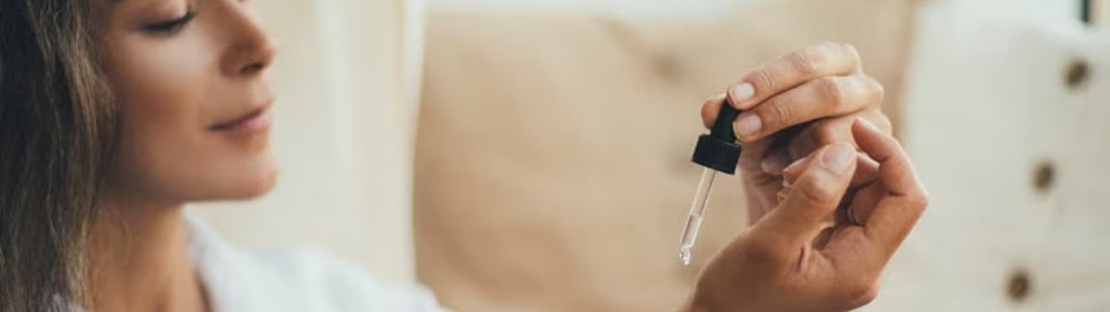 woman adding perfume to wrist with dropper